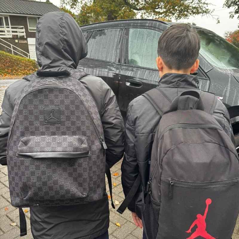 Two boys outside with their school backpacks