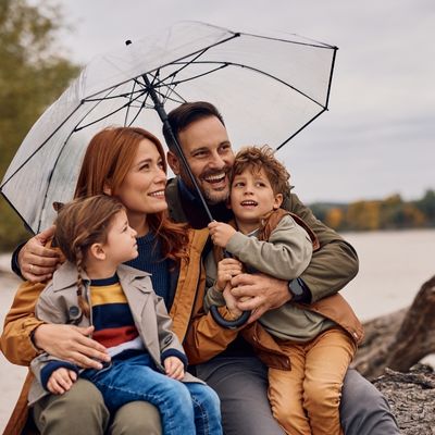 Happy family under umbrella enjoying in autumn day in nature