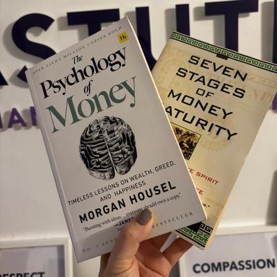 Hand holding two books about money in the air