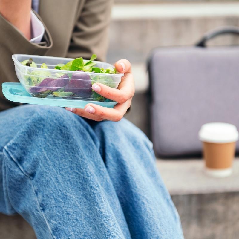 Snacking on salad pack lunch on concrete steps outdoors