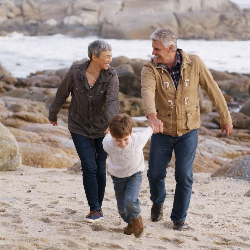 Grandparents holding hands with grandson at the beach