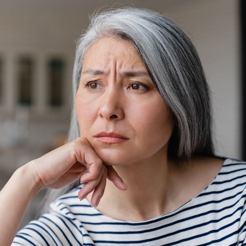 Middle-aged woman looking thoughtfully into the distance with a worried expression